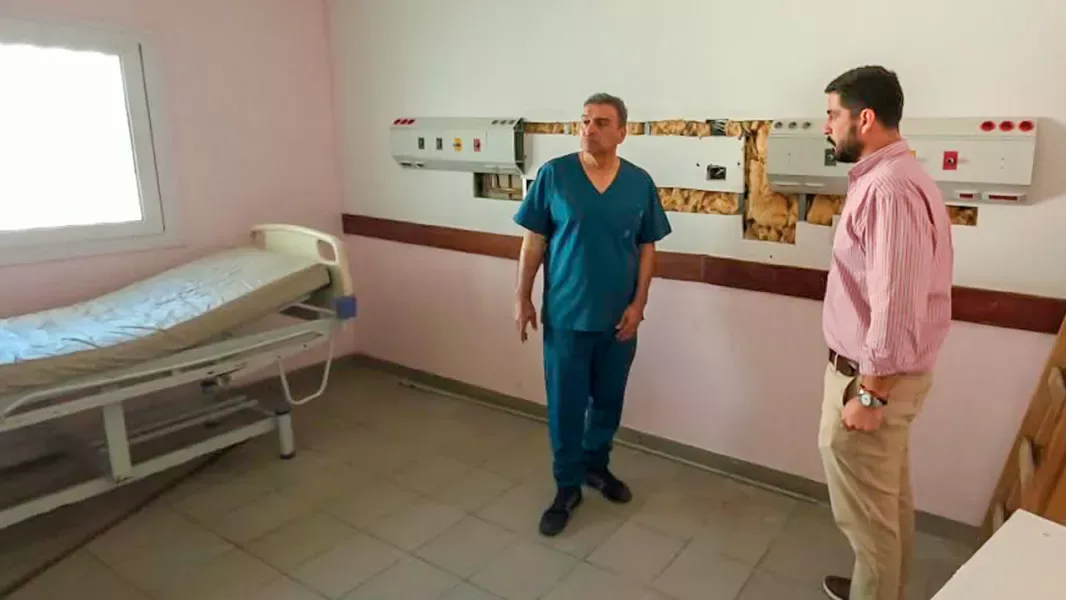 Dos hombres conversan en una sala del hospital San Roque de Embarcación, con una cama y un panel de gases medicinales todavía sin terminar de montar en la pared