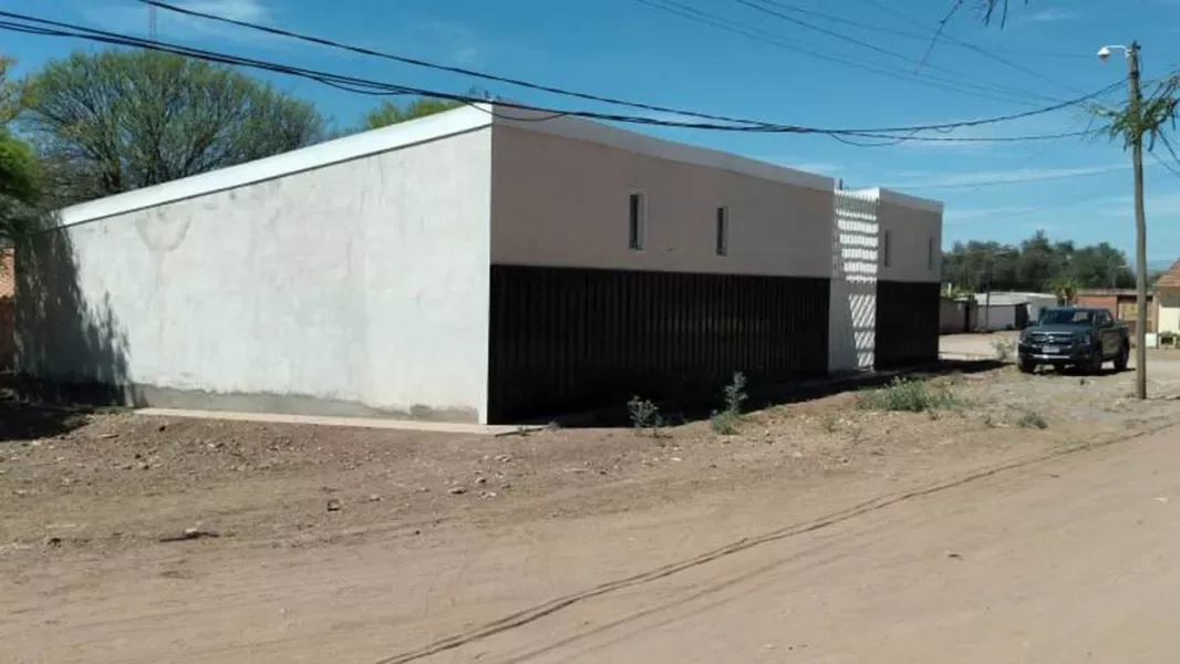 Vista exterior del nuevo centro de desarrollo infantil de Coronel Moldes: un edificio bajo, de frente blanco y gris con celosía, sobre una calle de tierra
