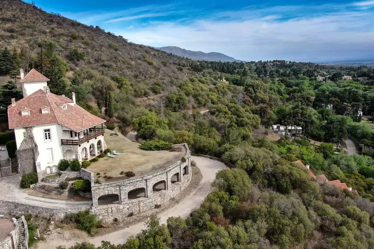 Fachada del Castillo Mandl en La Cumbre, Córdoba, rodeado de arboleda en las sierras
