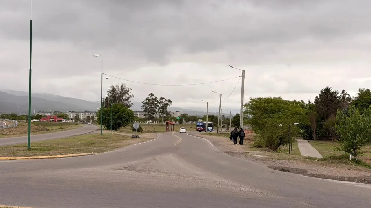 Colectora de avenida Bolivia en la zona norte de Salta, con un colectivo y peatones al fondo, en un día nublado