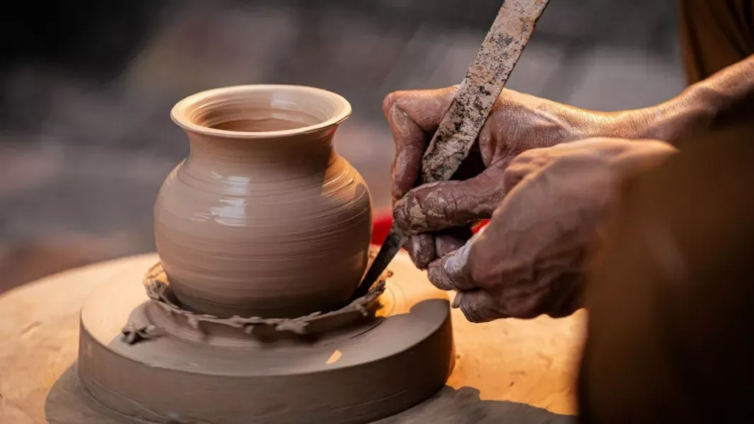Manos de un artesano dando forma a una vasija de barro en el torno