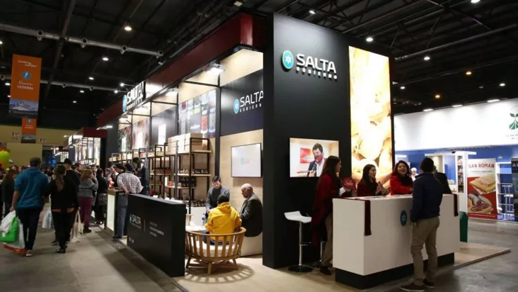 Stand del Gobierno de Salta en la feria Caminos y Sabores, con estantes de productos regionales y visitantes recorriendo el pabellón