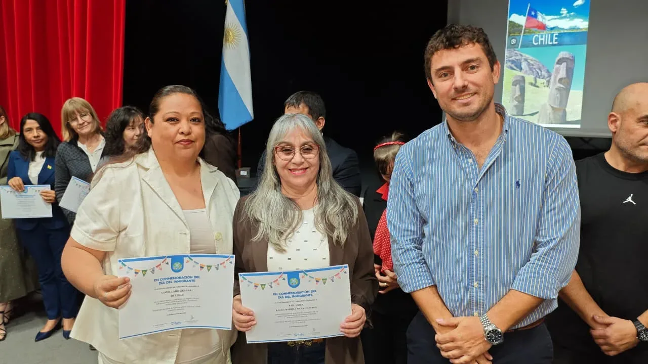 Mujeres sostienen certificados de reconocimiento en la ceremonia del Día del Inmigrante en Salta