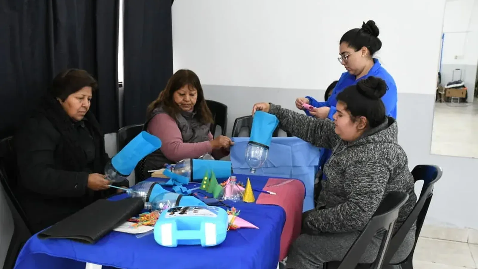 Un grupo de vecinas arma títeres con botellas de plástico recicladas sobre una mesa