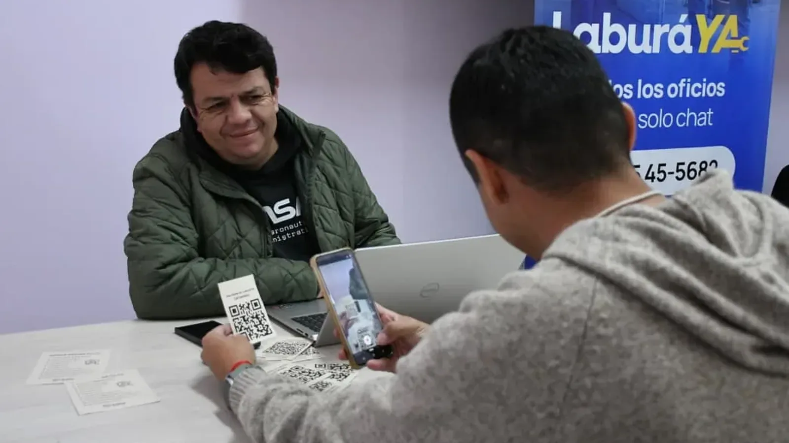 Un vecino escanea un código QR con su celular frente al puesto de asesoramiento de «Laburá Ya»