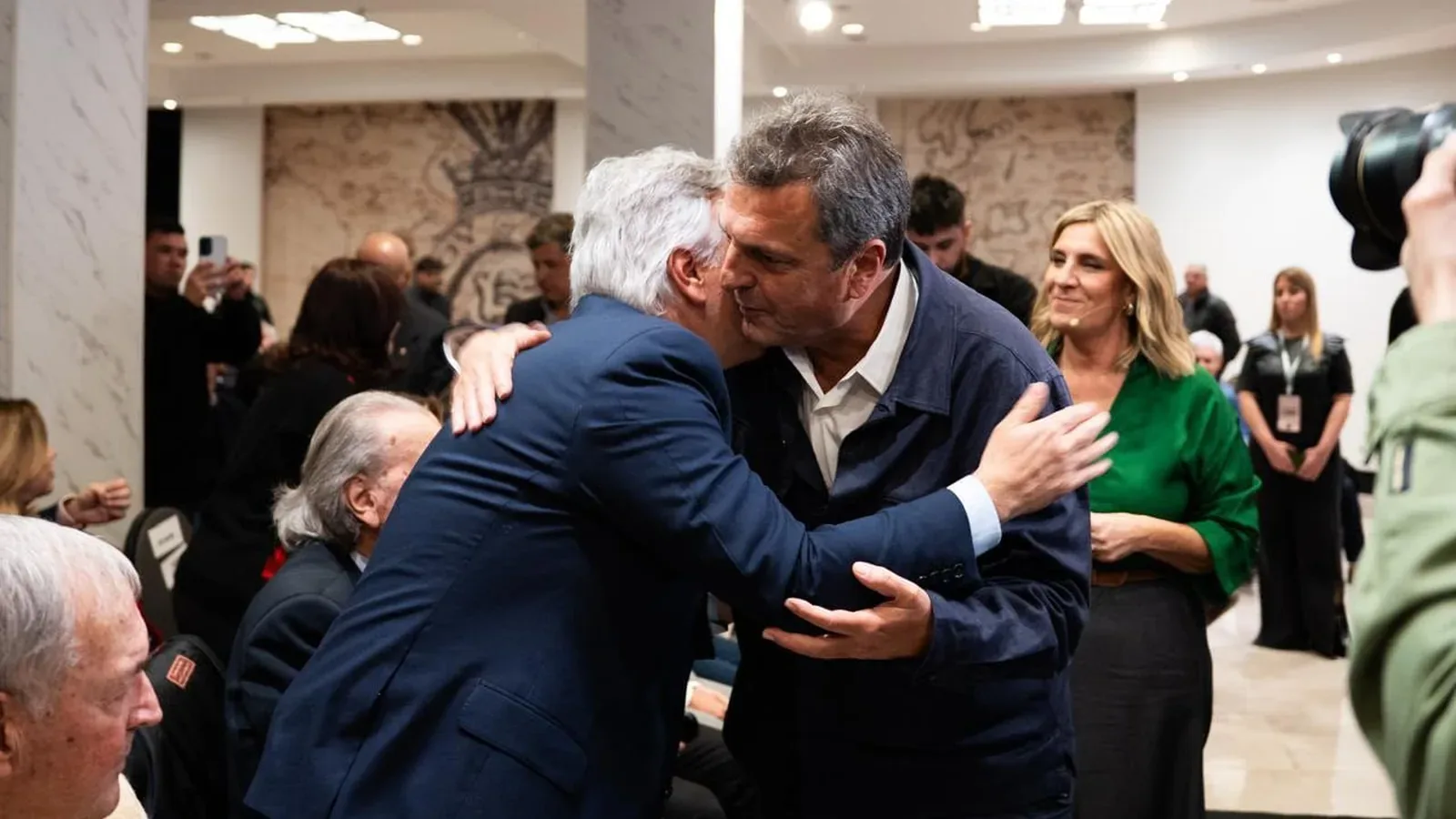 Dos dirigentes se abrazan durante el acto de homenaje, rodeados de asistentes y fotógrafos