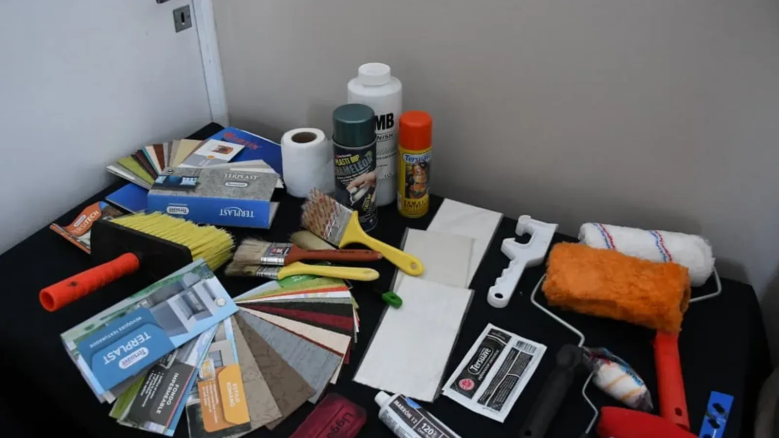 Herramientas y muestrarios de pintura dispuestos sobre una mesa para el curso de pintura de obra