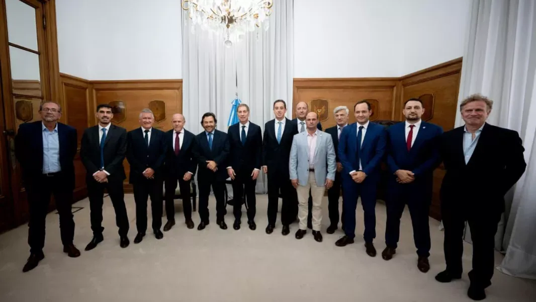 Integrantes de la comitiva salteña y funcionarios nacionales posan de pie, en fila, en un salón oficial frente a una bandera argentina