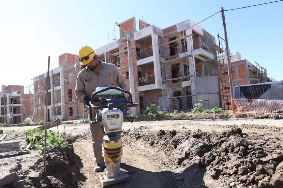 Un obrero de la construcción compacta el suelo frente a los edificios de un barrio de viviendas en obra en la zona norte de la ciudad de Salta