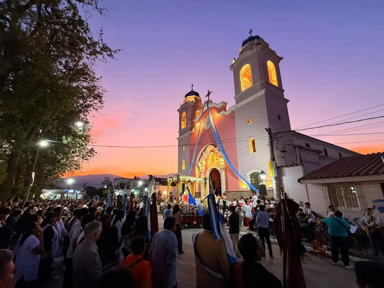 Procesión con la imagen de la patrona frente a la iglesia de Rosario de Lerma, al atardecer y con el pueblo en la calle