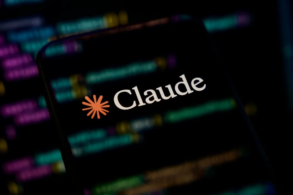 Celular con el logo de Claude sobre un fondo de líneas de código desenfocadas